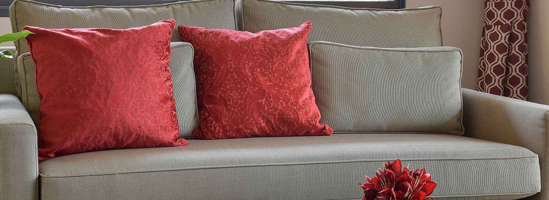 comfortable sofa with red pillows and red book on table